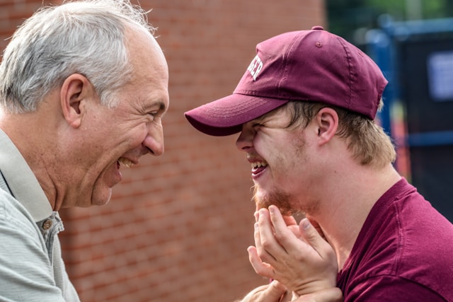 A young man with disabilities laughs with his father